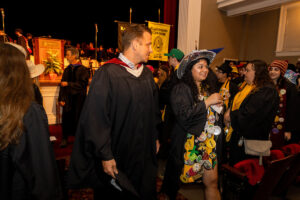 A man and a woman walk down the center aisle of an auditorium 