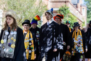 Students wearing graduation robes and funny hats walk on campus 