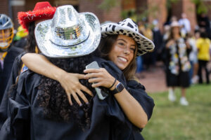 Two students in cowboy hats hug
