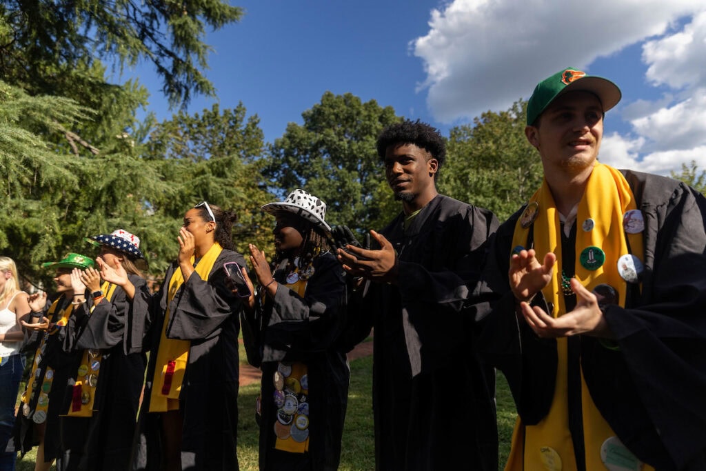 STudents stand together, clapping and singing