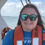 A woman in a life jacket holding a small shark