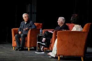 Nick Ut, Sue Ott Rowlands, and Kim Phuc Phan Thi sit on the stage in Thoresen Theatre during a special Q&A