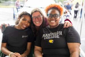 Three people pose for a photo together during a tailgate 