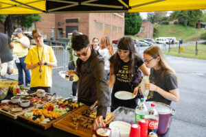 People try the food set out for a tailgate event 