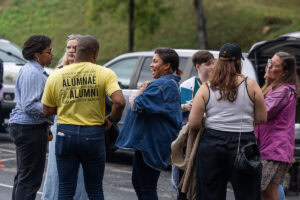 A group of people talk and laugh during a tailgate event 
