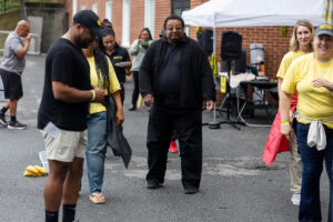 Several people stand together outside, talking during a tailgate event 