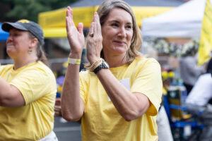 A woman in a yellow shirt claps her hands 