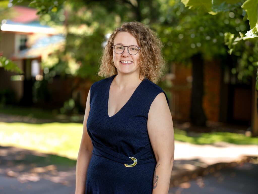 A woman poses for a portrait with trees behind her