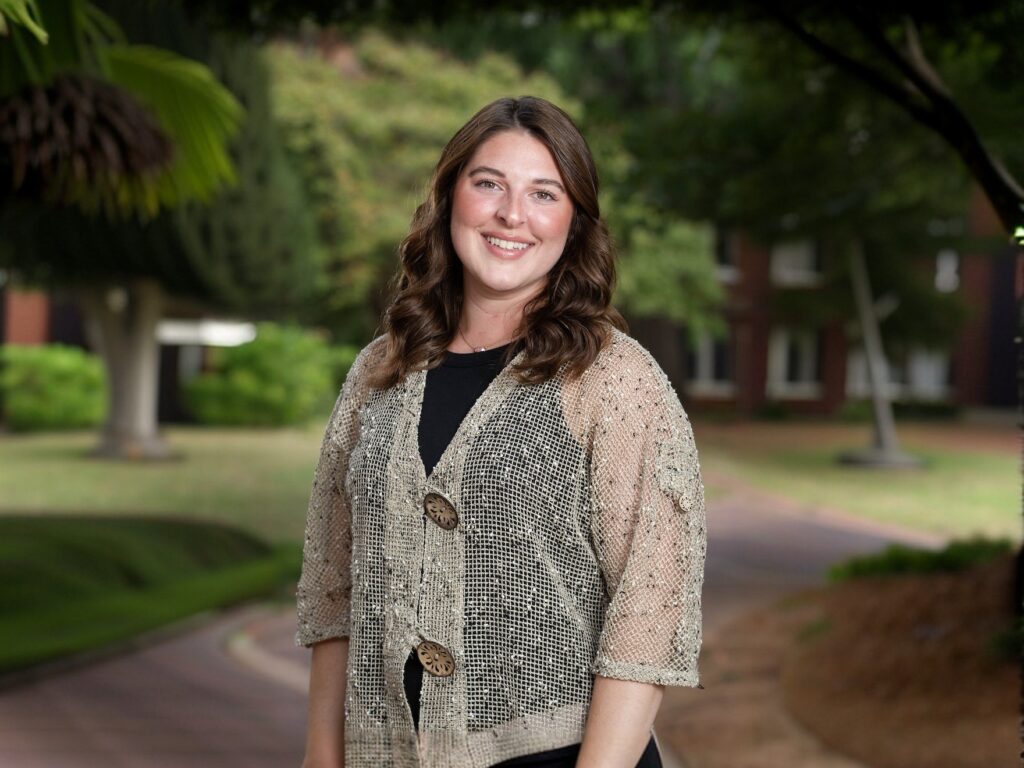 A woman poses for a photo with trees in the background