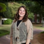 A woman poses for a photo with trees in the background