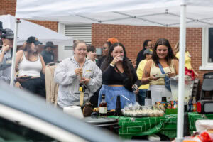 Several students make plates during a tailgate event