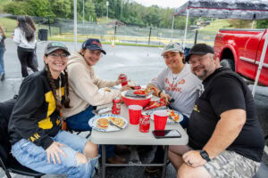 A group of four people sit together at a table during a tailgate