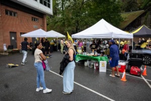 Two people talk with white tents in the background during a tailgate event 