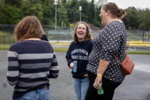 A group of people talking, with the woman in the middle laughing 