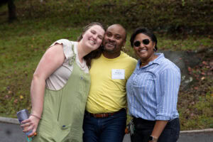 Two women and a man pose for a photo together, smiling 