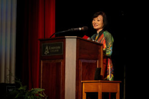 Kim Phuc Phan Thi stands behind a podium, speaking to the audience 
