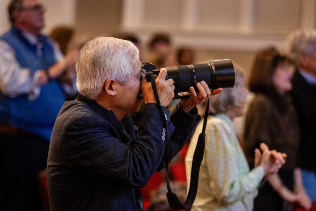 Nick Ut points his camera at the stage during an award ceremony