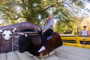 A student rides a mechanical bull