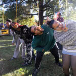 Donuts hang from above, and a line of students try to eat them with their hands tied behind their backs Donuts hang from above, and a line of students try to eat them with their hands tied behind their backs