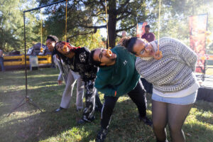 Donuts hang from above, and a line of students try to eat them with their hands tied behind their backs