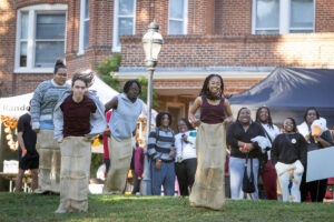 Students compete in a potato sack race on front campus, with Main Hall in the background