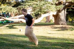 A male student jumps across front campus in a potato sack
