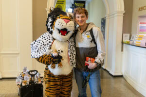 A student poses for a picture with the Wanda WildCat mascot, dressed up as Cruelle De Ville for Halloween