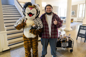 A student poses for a picture with the Wanda WildCat mascot, dressed up as Cruelle De Ville for Halloween
