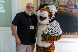 A man poses for a photo with Wanda WildCat, dressed up as Cruella De Ville for Halloween