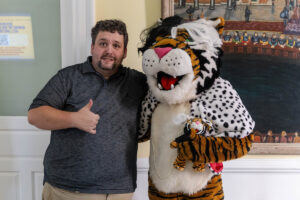 A man poses for a photo with Wanda WildCat, dressed up as Cruella De Ville for Halloween