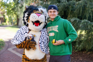 A student poses for a picture with the Wanda WildCat mascot, dressed up as Cruelle De Ville for Halloween