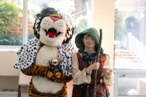 A student poses for a picture with the Wanda WildCat mascot, dressed up as Cruelle De Ville for Halloween