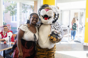 A student poses for a picture with the Wanda WildCat mascot, dressed up as Cruelle De Ville for Halloween