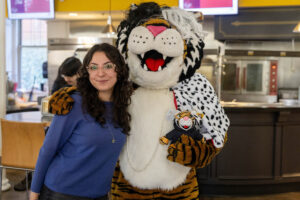 A student poses for a picture with the Wanda WildCat mascot, dressed up as Cruelle De Ville for Halloween