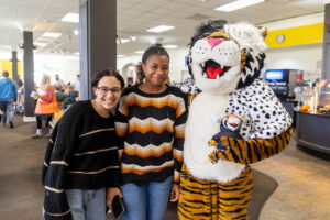Students pose for a picture with the Wanda WildCat mascot, dressed up as Cruelle De Ville for Halloween