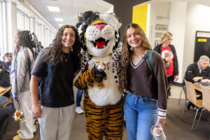 Students pose for a picture with the Wanda WildCat mascot, dressed up as Cruelle De Ville for Halloween