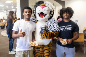Students pose for a picture with the Wanda WildCat mascot, dressed up as Cruelle De Ville for Halloween