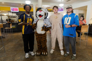 Students pose for a picture with the Wanda WildCat mascot, dressed up as Cruelle De Ville for Halloween