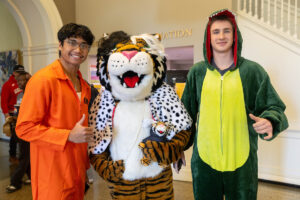 Students pose for a picture with the Wanda WildCat mascot, dressed up as Cruelle De Ville for Halloween