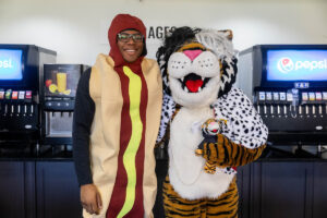 A student dressed as a hot dog poses with Wanda WildCat, dressed as Cruella De Ville, on Halloween