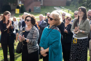 Two women in sunglasses listen in a crowd of people