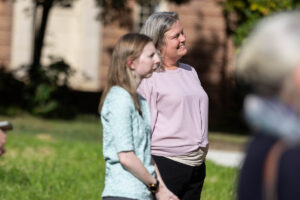 Two people stand outside, looking in the same direction