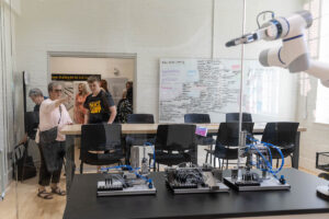 A group of people standing around a table with a robot.