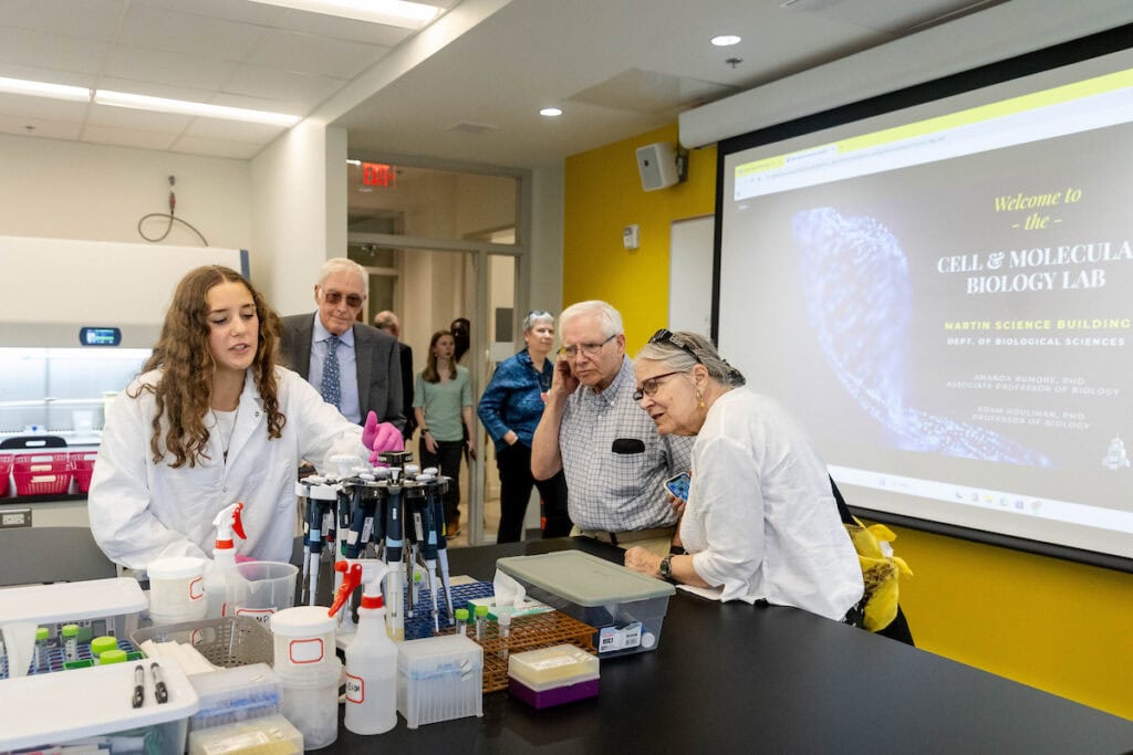 People in lab coats and glasses looking at a screen.