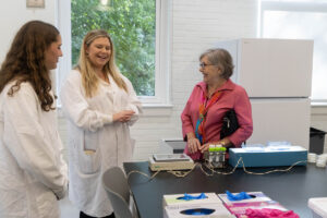 A woman in a lab coat speaks to people in her lab