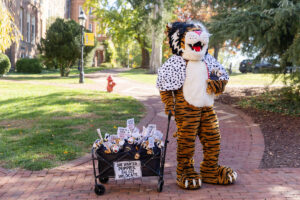 Wanda WildCat dressed as Cruelle De Ville for Halloween, with a black-and-white wig, Dalmation-print cape, and a wagon full of mini Wandas disguised as dogs