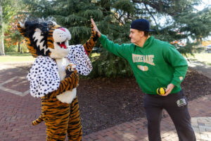A student high-fives Wanda WildCat, dressed up as Cruelle De Ville for Halloween
