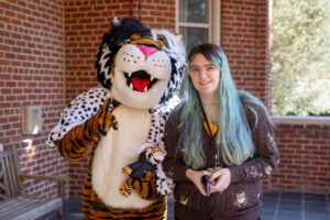 A student poses for a picture with Wanda WildCat, dressed up as Cruelle De Ville for Halloween