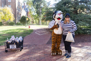 A woman dressed as a robber poses for a photo with Wanda WildCat on Halloween