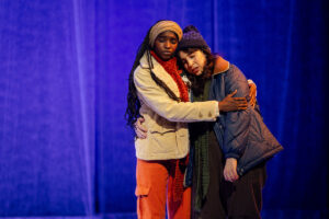 Two actors embrace on stage 